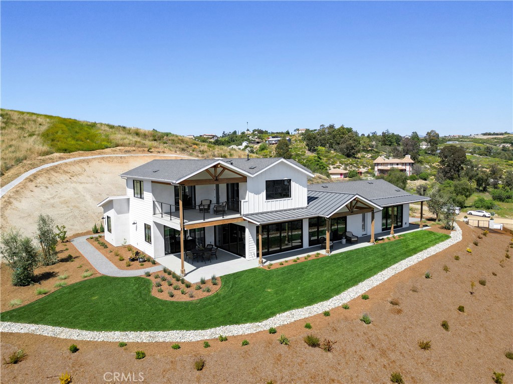 Welcome to this exquisite brand-new custom-built home. Nestled in the heart of the beautiful Temecula wine country. Paid for solar and stunning views. This stunning residence boasts 5 bedrooms, 4 bathrooms, and an expansive 3,811 square feet of meticulously designed living space. From the moment you approach, you are greeted by the charm of its unique architecture and allure. As you enter through the grand front door, you step into a welcoming foyer adorned with elegant finishes and designer lighting, setting the tone for the luxurious modern atmosphere that permeates throughout the home. The open floor plan seamlessly connects the living spaces, creating an inviting and functional layout perfect for both everyday living and entertaining. The gourmet kitchen is a masterpiece, featuring custom cabinetry, and a large center island with a sleek granite countertop. Whether you're a culinary enthusiast or enjoy casual family meals, this kitchen is sure to inspire your inner chef. The adjacent dining area provides a picturesque setting with large windows offering views of the surrounding vineyards and rolling hills. The living room is a cozy retreat, anchored by a stylish fireplace and bathed in natural light that filters through the strategically placed windows. Hardwood floors, recessed lighting, and soaring 8 ft interior doors add warmth and sophistication of the space. The master suite is a sanctuary of relaxation, boasting a spacious bedroom with a private balcony overlooking the vineyards. The ensuite bathroom is a spa-like haven, complete with a soaking tub, a walk-in shower, and dual vanities, all finished with high-end materials and impeccable craftsmanship. The additional four bedrooms offer generous space, each uniquely designed to provide comfort and style. The accompanying bathrooms are appointed with modern fixtures and luxurious details. The outdoor spaces are thoughtfully landscaped, with a covered patio for al fresco dining. The backdrop of hills creates a tranquil ambiance that enhances the overall appeal of the property. This custom-built home not only offers a luxurious and comfortable lifestyle but also provides a unique connection to the beauty of wine-country living. With attention to detail at every turn, this residence is a testament to quality craftsmanship and timeless design, inviting you to experience the epitome of refined living in this enchanting locale. Close to the local wineries, top-rated schools, & freeway.
