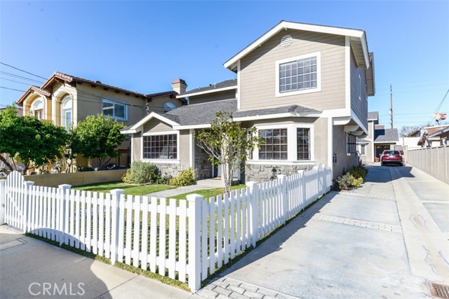 White picket fence surrounds the grassy front yard