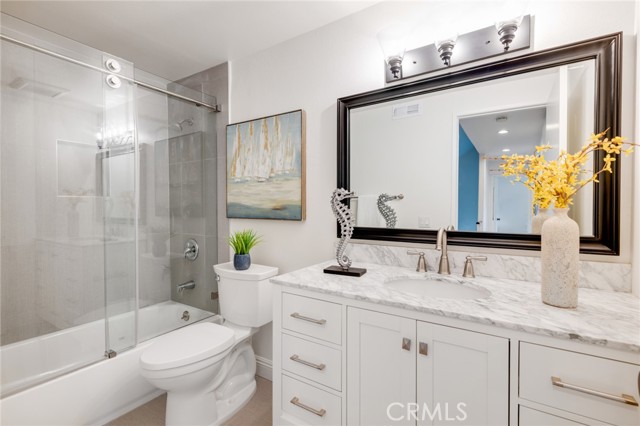 New vanity, tub, tiles and shower glass enclosure gives this hallway bath a refreshing feel.