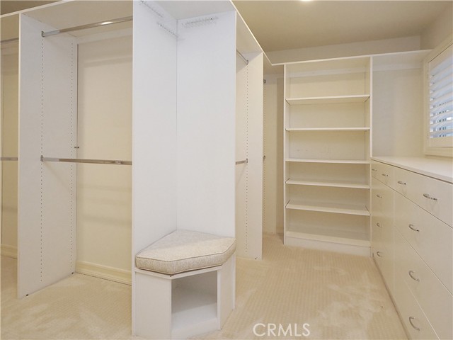 Primary walk-in closet with built-in dressers and shelves