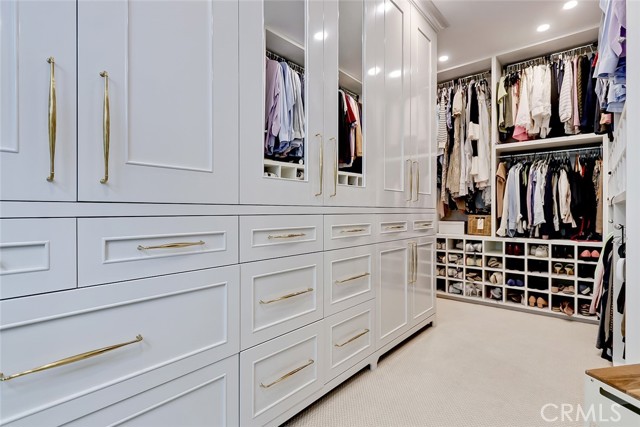 Closet with walls of custom built-ins and double rows of pull down hanging rods