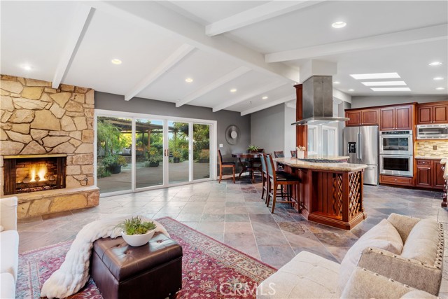 The family room area of the great room with vaulted open beamed ceilings, warm PV Stone fireplace, slate floors, recessed lighting.
