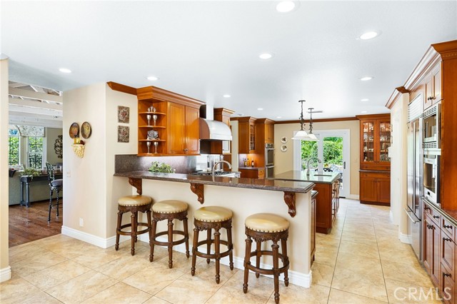 Spacious kitchen with custom cabinetry, granite counters, stainless steel appliances, and a breakfast bar.