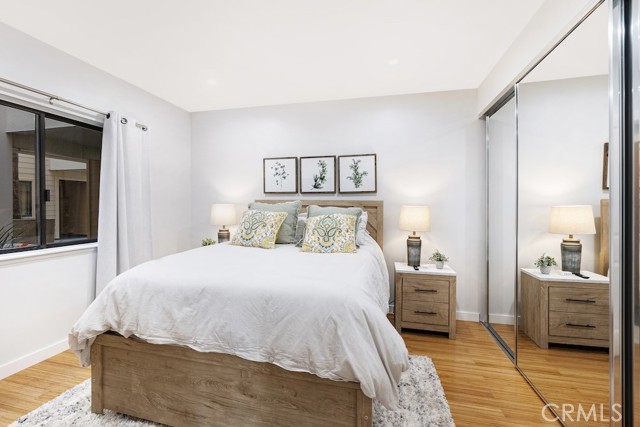 2nd bedroom featuring mirror closet doors and wood flooring