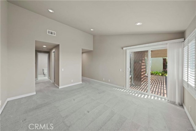 Looking from the master bedroom towards the back patio on the right and the master bath on the left. Neutral carpet and paint pallete, recessed lighting, and plantation shutters blend to create a relaxing retreat.
