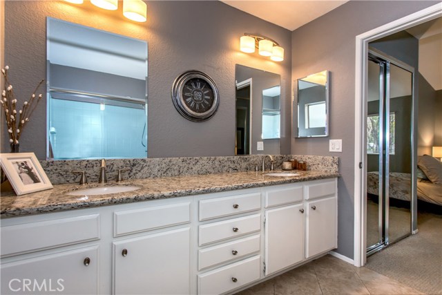 Stunning master bathroom featuring granite countertops, dual vanities, custom lighting, custom hardware, tile floors.