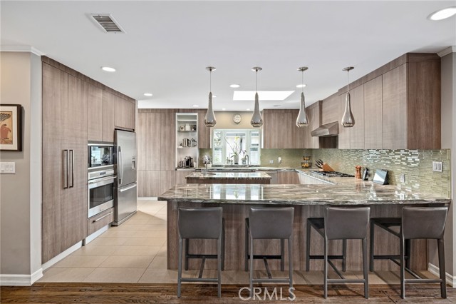 From one of the open living area spaces looking into the kitchen and island. Beautifully appointed. Wolf appliances, custom Italian cabinets, granite counter top, custom tile floor and more!