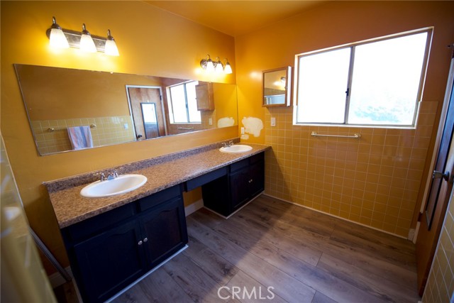 Primary en suite bathroom with dual sinks and vanity area. New vinyl laminate flooring and exhaust fan.
