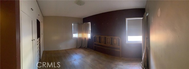 This panorama shot of a bedroom shows custom built in dresser and closets and lots of light