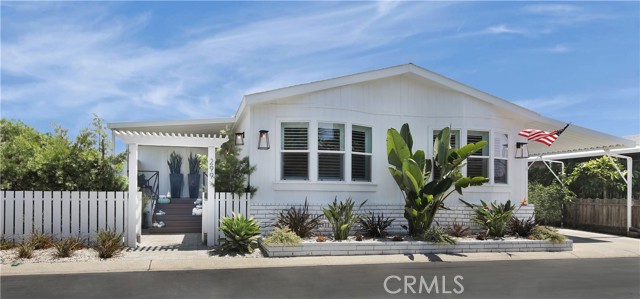 Front view with formal entry on left and carport with rear entrance to the right. Grounds are professionally landscaped.