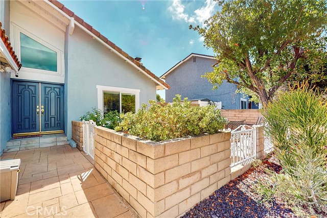 Double front entry door. To the right is a small gate to front patio landscaped with white roses.