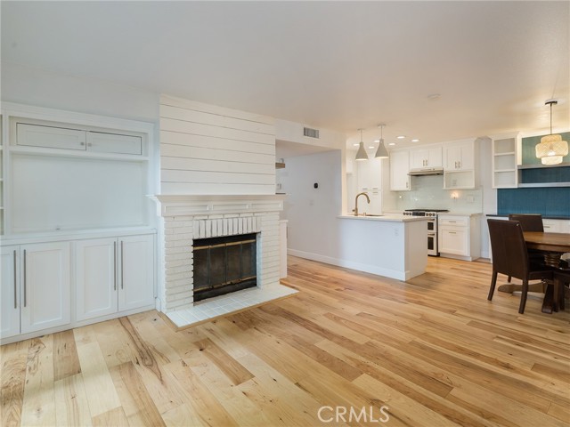 Gorgeous wood flooring, custom cabinetry, shiplap above brick fireplace, and open floorpan