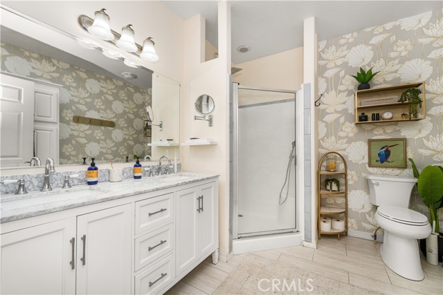 Primary bathroom with walk-in shower and newer textured wallpaper.