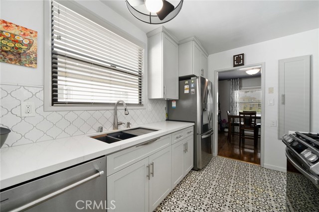 The kitchen has been upgraded with newer cabinets, quartz countertops, a custom backsplash, and stainless steel appliances, adding modern flair to the home.