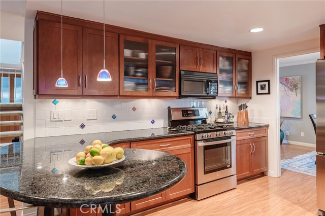 Gleaming granite, shiny stainless, and artsy glass pendant lighting