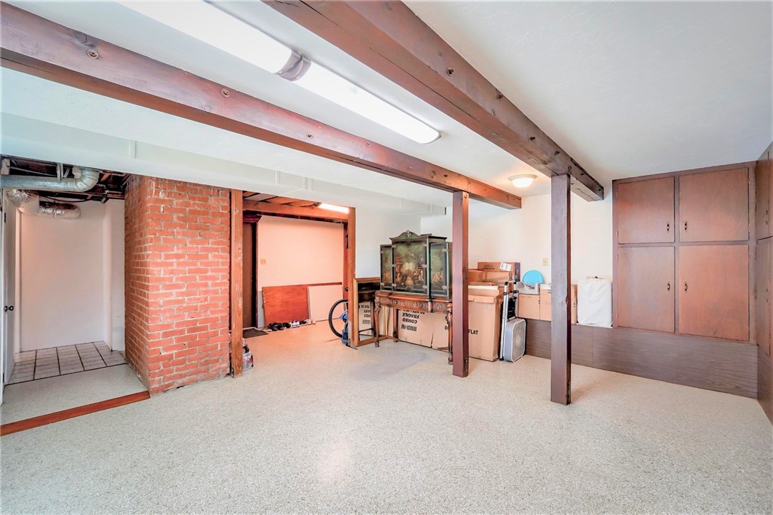 The huge bonus room is lined with storage cabinets. At the far end on the left, is a separate storage room and the entry door to the attached 2-car garage.