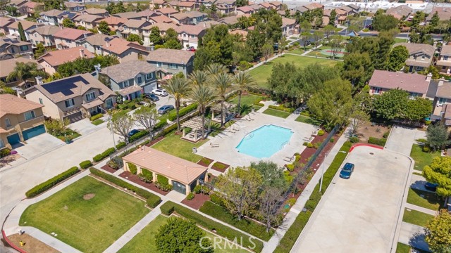 An aerial view of a residential community with a swimming pool and a park area with palm trees.