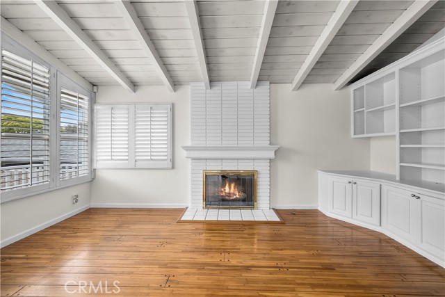 Living Room With Fireplace And Built-in Cabinetry. Wood Beam Vaulted Ceiling, Plantation Shutters And Hardwood Floors Throughout.