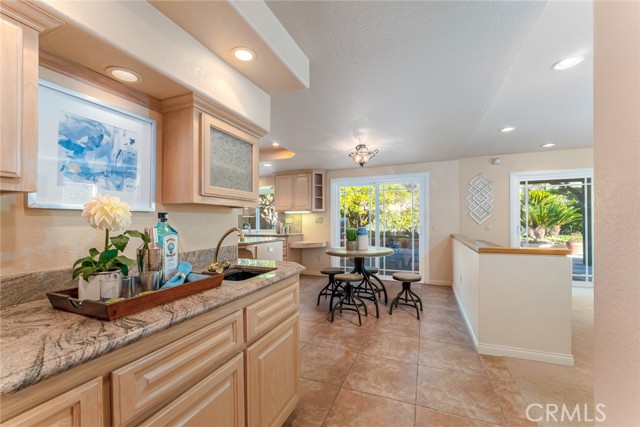 Bar with custom recessed lighting and custom cabinetry leading to kitchen