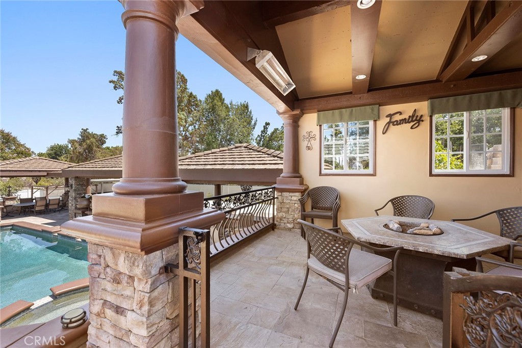 Raised gated Loggia overlooking Sports Court, pool & grounds, with lots of detail in design. Built-in ceiling beams, recessed lighting, stone columns, stone flooring, and gas heaters.
