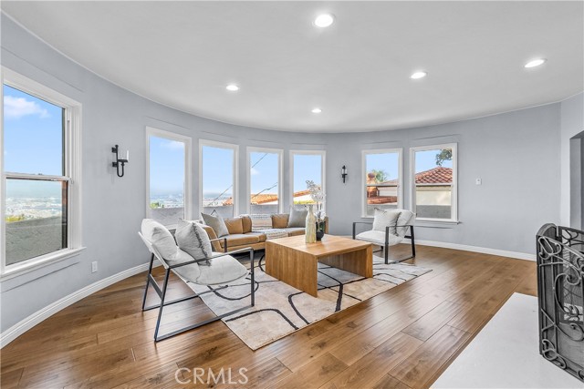 The living room is appointed with rich hardwood floors, an elegant stone fireplace, and subtle designer tones.