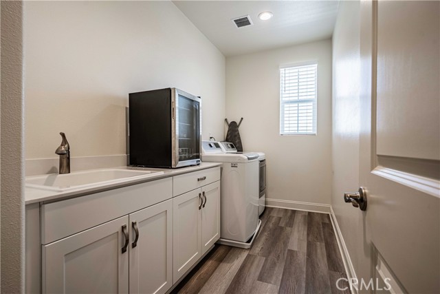 Laundry room is waher/dryer hook up at the end of the room. Oversized sink greets you in white with dolphin grey cupboards and the same stainless steel hardware. Wood laminatte flooring, recessed lighting and a window here.