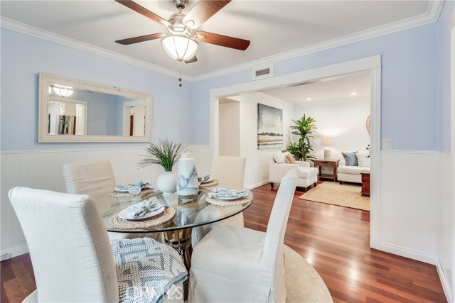 Newly painted dining room with wainscotting, hardwood floors and more opens to both the kitchen and family room