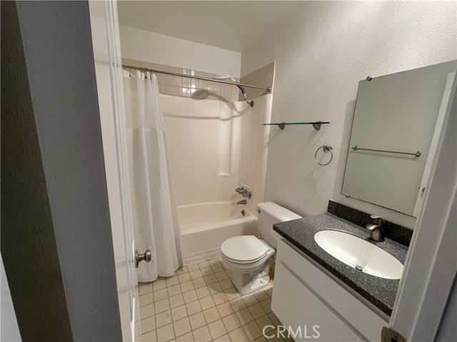 A nice bathroom equipped with a shower/tub, granite counter and tile floor!