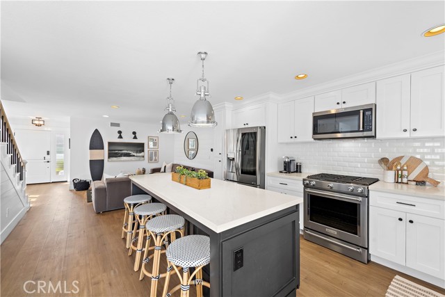 Open kitchen overlooks backyard and opens to downstairs sitting room with Samsung Art Frame TV.