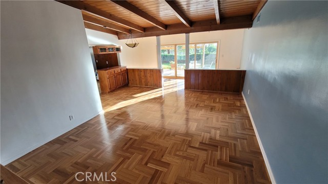 Living room highlighting vaulted, wooden beamed ceiling, and rear patio windows.