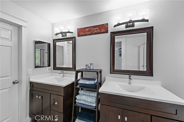 Primary bathroom with dual vanities and a walk-in closet.