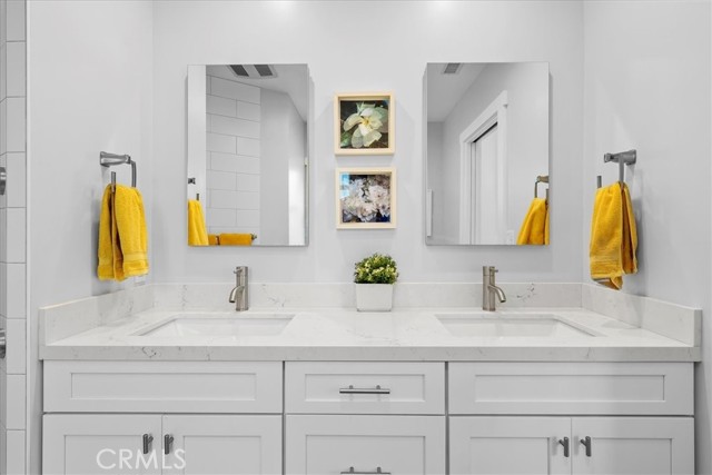 Dual sinks with quartz countertops and built in medicine cabinets.