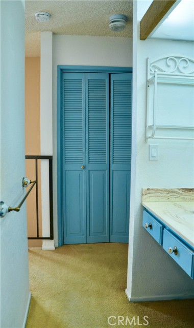 Looking back from primary bathroom toward the hall closet upstairs with laundry inside and additional shelving.