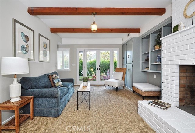 This third living space downstairs boasts seagrass carpet, exposed wood beams, built ins, and opens to the outdoor living space.
