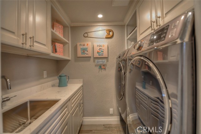 Down stairs laundry room with quartz counters and a stainless steel sink.  And the laundry chute empties above the washer!