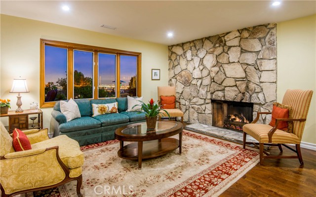 Living room with fireplace, hardwood floors, bay window, recessed lighting and view.