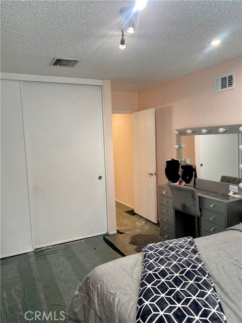 Another view of the primary bedroom with track and recessed lighting, closets and views to backyard.