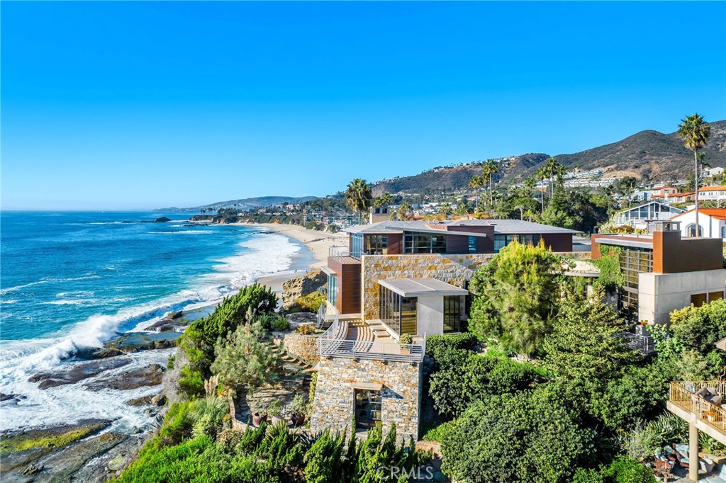 15 Camel Point is an exquisitely executed contemporary oceanfront offering with rare direct beach access via the estate’s private staircase. Sited on over a third of an acre at the end of the point just south of the famed Montage Laguna Beach, this architecturally significant property designed by Bill Murray features stunning 270-degree views of the Pacific Ocean. The interiors, curated by Tommy Chambers, are a study in form and function: concrete, glass, natural stone, and wood elements are seamlessly combined throughout. The main level of this approximately 5,100 square foot estate located in one of Orange County’s most sought-after gated enclaves features distinct entertaining areas, with walls of glass on all sides and views of the Pacific Ocean beyond.  Numerous multi-paneled doors expertly connect the interior with the property’s several large patio areas for the essential indoor-outdoor California living experience. The primary suite occupies the majority of the upper level and is comprised of an ocean-facing bedroom, dream bathroom with stand alone tub, a massive master closet, and an adjacent home office. The lower floor can be utilized as a home gym, play area, or converted into additional sleeping quarters. A garage with a hydraulic lift is a car lover’s dream. The numerous spacious outdoor patios offer an ideal setting for enjoying panoramic views spanning from Dana Point to Palos Verdes in an ultra-private location, with West Street, Treasure Island, and Aliso Beaches just steps away. Property is currently under major construction and around year out from final completion.