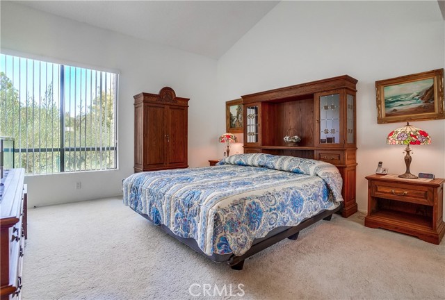Master bedroom with tall vaulted ceiling and views of treetops and tennis courts