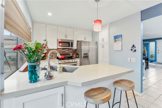 Blinds at window open from top or bottom. Kitchen was newly updated in the last three years with shaker cabinets and quartz counters, pendant lighting, recessed lighting, and backsplash. Appliances to remain. Just enough space to casually sit at the counter.