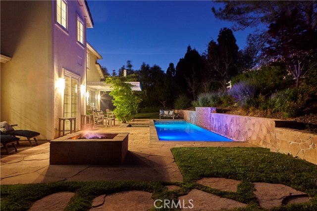 Twilight view of back yard with pool lights on