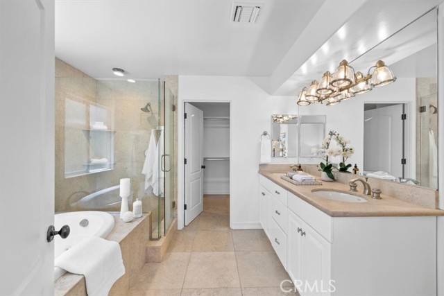Primary bathroom with dual vanities and large walk in closet
