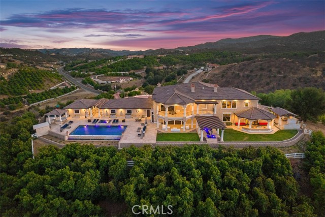 "PRICE IMPROVEMENT": NO MANSION TAX: Welcome to Villa Dolce Vista. Commandingly positioned atop 20.39 ACRES at the north point of the EQUESTRIAN COMMUNITY of La Cresta, this Italian inspired masterpiece offers luxury amenities appreciated by the most discerning buyers. Impressive private GATED COMPOUND offers uninterrupted panoramic VIEWS of mountains, city lights, and the Temecula Valley. Encompassing nearly 14,000 SF, the resplendent home includes 5 EN-SUITE BEDROOMS, 8 BATHROOMS, a grand foyer with DUAL STAIRCASES and 24’ ceiling, elegant wood paneled STUDY, FORMAL DINING ROOM with fireplace and expansive city light view. Incredible CHEF’S KITCHEN includes a 20’ granite topped island, COPPER CEILING and LEDGER STONE WALLS. Extraordinary PRIMARY SUITE offers a FIREPLACE, BALCONY with staggering city light views, OPPULANT BATH with dual water closets, vanity areas, marble spa showers, and Jacuzzi tub. Massive GAME ROOM with full wet bar and access to the outdoor travertine deck with FOUNTAINS, INFINITY EDGE JEWEL SCAPE POOL AND SPA and two full outdoor BBQ kitchens. EIGHT CAR GARAGE with built in cabinetry. This SMART HOME is equipped with $155,000 in electronics that provides you with touch screen devices throughout the home. For extended family, a 1,977 SF SINGLE STORY 2 BEDROOM, 2 BATH BUNGALOW with two- 2 car attached garages. Energy efficient with a 47 KW 136 PANEL SOLAR SYSTEM powering both the main home and bungalow. 53’x40’ RV GARAGE totaling 2,120 SF for storage of two 45’ motorhomes plus all the toys. INCOME PRODUCING HAAS AVOCADO GROVE with automatic fertilization system and WELL watered with two 5000 gallon holding tanks. Additional building pad for future barn, tennis court or helipad. The La Cresta community is located mid-way between Orange County and San Diego County with convenient access to Ontario, San Diego, and John Wayne International Airport. This stunning estate is just minutes from the members only Bear Creek Golf Club offering a Jack Nicklaus designed golf course, tennis, and fine dining as well as the growing Temecula wine country.