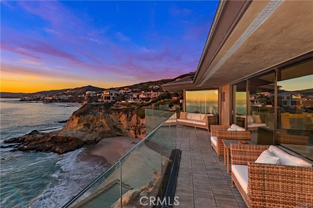 Welcome to one of the world’s finest oceanfront estates, where a rare double bluff-top homesite of nearly 20,000 s.f. and a fully rebuilt custom residence combine to create the most unique living environment in Laguna Beach. Premium northwest-facing views capture the ocean, beach, crashing waves, shimmering lights, and Catalina from every room of the contemporary masterpiece in guard-gated Three Arch Bay. A dramatic promontory setting is secluded behind a custom entry gate and features a circular drive, park-like grounds, and a spacious courtyard. Wraparound view decks offer steps down to bedrock, where a private saltwater pool is replenished naturally with the tide. Neither the location—which spans 150' at the water’s edge—or the pool would be granted permission by today’s codes, making this a truly rare opportunity. Approx. 5,144 s.f. with 4 bedrooms, 5 full baths, and 2 half baths, the open and airy residence showcases soaring ceilings, a seamless living and dining area, a home theater, an extensive glass-enclosed wine storage wall, and a sleek kitchen with enormous island and top-end appliances. Just inside the entry gate, a separate structure is ideal as a gym, studio, or office.