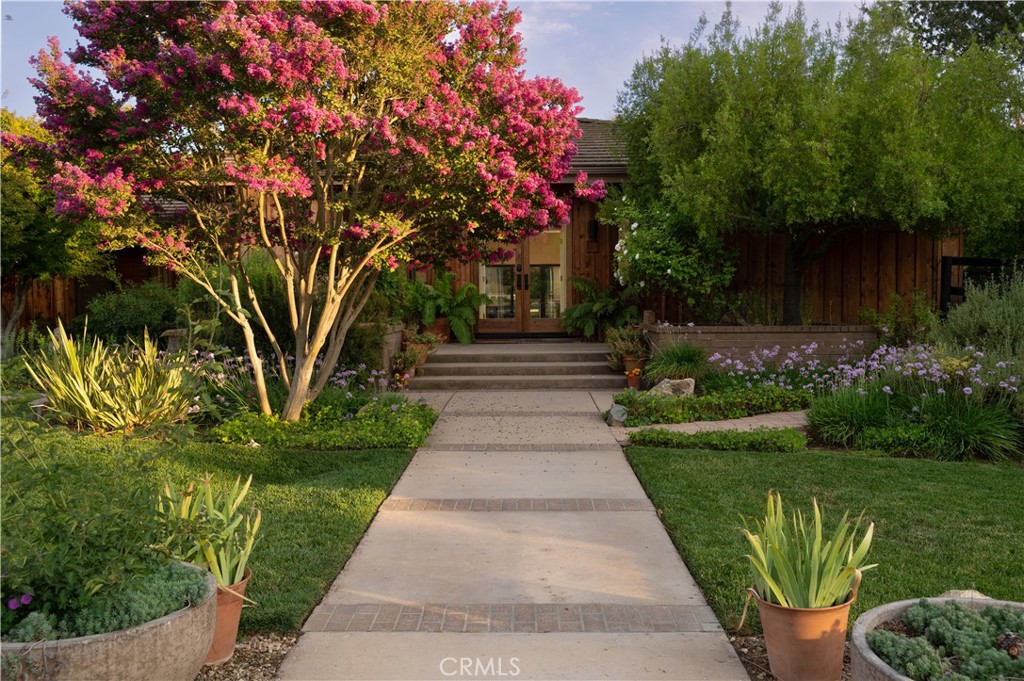 770 Entrance Road Solvang, California A hidden treasure beyond the tree-lined drive, you have reached a home that exudes a mindful presence that invites you to investigate. This spacious 2,994sf Redwood Sided home provides both a practical and aesthetically pleasing experience. Through the glass entry into the foyer and formal living room with stone front fireplace and high ceilings, you are greeted with views of welcoming patio, breathtaking landscaping and irrigated pastures. The wood floors guide you through the formal dining room into an expansive kitchen and family room with soaring ceilings, fireplace, built-ins and slate tile kitchen island. This kitchen has it all; gas stove top, double wall ovens, walk in pantry and enough cabinet space for every cooking appliance. 2 bedrooms, an office, full bath, laundry room, and mud room are situated at the East end, while the primary bedroom with fireplace, vaulted ceilings, private patio with spa, and en-suite bath are located at the West end. The primary en-suite bath includes a soaking tub, double-headed shower and walk-in closet with island. A private suite located through a breezeway that includes private bath and walk in closet.
In the Valley's delightful climate, the outdoors is the place to be. Meander through the matured landscaped 5+ acres that includes, Sycamores, Crepe Myrtles much more. There is public water AND a private well. Walking paths from the entertaining patio lead you through the grounds to an outbuilding suitable for an art studio, meditation studio or yoga room.
There is a 6-Stall Shedrow MDBARN with turnouts including tack room, wash rack, vet room/laundry room and office. Nearby find the round pen, dressage arena with viewing stand and chicken coop. Through the aisle between irrigated pastures is the 1 bedroom, 1.5 two-story second residence. With its own address, driveway and private access, this residence is a great escape for extended family and friends or generating its own income. Invisible to the naked eye, but oh so important, are the solar and reverse osmosis systems in place helping the ranch and keeping it healthy.
When you and your guests tire of your pastoral surroundings, travel just minutes down the road to enjoy some of the Valley's finest restaurants, wine tasting or shopping. Whether you are a horse aficionado, bask in home entertaining or absolutely cherish your privacy, this beautiful and private ranchette has a little something for everyone.