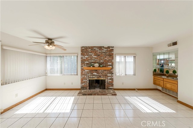 Great room feature cozy brick fireplace, ceiling fan and a wet bar.