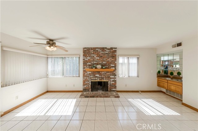 Great room feature cozy brick fireplace, ceiling fan and a wet bar.