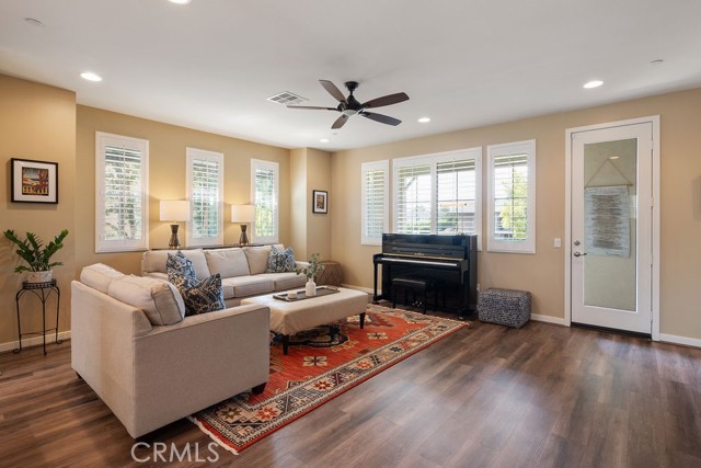Living room appointed with ceiling fan, recessed lights, shutters and vinyl laminate flooring