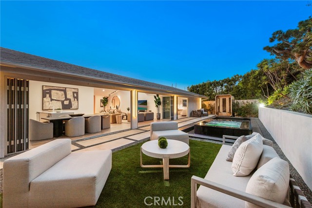 1318 Outrigger Drive Corona del Mar, California Nestled within the coveted community of Harbor View Hills South, 1318 Outrigger Dr is a newly rebuilt and thoughtfully expanded single-story home that seamlessly combines contemporary elegance with a nod to mid-century modern design. Offering a perfect blend of form and function, this residence is a sanctuary of style, comfort, and sophistication. Boasting a grand scale open-concept layout, the home is bathed in natural light, with elevated ceiling heights enhancing the sense of space throughout. At its heart lies an avant-garde culinary experience, featuring both a front and back kitchen design. The primary kitchen showcases a waterfall-edge island with bar seating, a wine fridge, and sleek finishes, while the European-inspired back kitchen is equipped with premium Miele appliances, including a cooktop and dishwasher—perfect for hosting with ease and flair. Seamlessly blending indoor and outdoor living, the home features four sets of multi-panel fluorocarbon aluminum bi-folding doors with smart battery blinds throughout, connecting both the front and back oasis. The entertainer’s front yard boasts ample seating and multipurpose turfed area, while the rear features an inviting pool, spa, dedicated BBQ area, sauna, and a stylish outdoor lounge area adjoining the kitchen and dining spaces. Each of the four bedrooms offers its own walk-in closet and en suite bath, ensuring privacy and luxury for every occupant. The primary suite is a true retreat, complete with lounge area and a spa-like bathroom inspired by the timeless elegance of Tiffany & Co. A sleek Saint Laurent inspired powder room adds convenience and sophistication for guests. From the moment you enter, you are greeted by an expansive front yard leading to a versatile ancillary space with vaulted ceilings—ideal for a home office, gym, studio/media room, or optional 5th bedroom. The home is further enhanced by a spacious three-car garage featuring oversized 9’x8’ openings and smart LiftMaster motors. Beyond the home, residents of Harbor View Hills South enjoy a lifestyle of unparalleled convenience, with close proximity to world-class beaches, upscale shopping, fine dining, parks and trails, and top-rated schools. Discover a home where modern luxury meets timeless design, set against the backdrop of one of Corona del Mar’s most desirable communities.