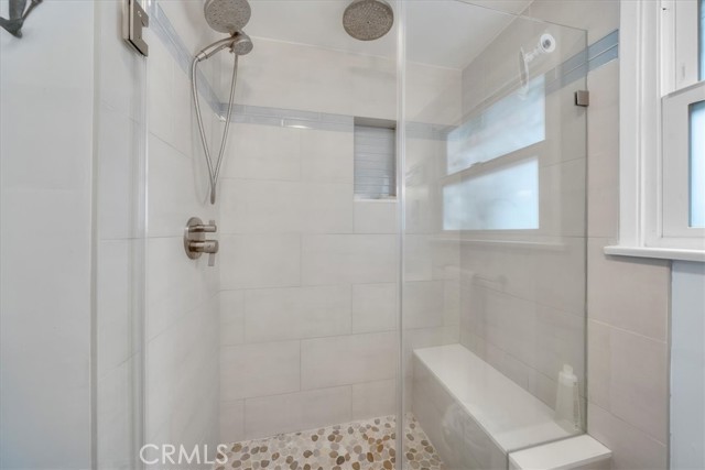 Updated shower in bathroom with in shower bench and glass doors